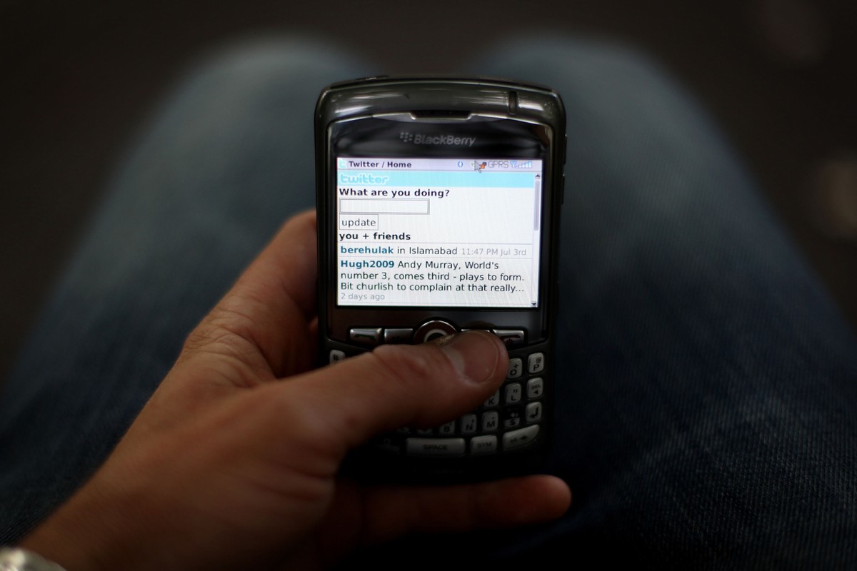 Antiquated mobile phone, digital display screen shows rudimentary UI from the original Twitter application.